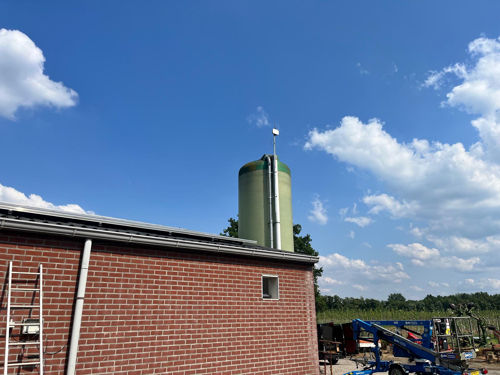 Farm silo antenna installation with red brick barn