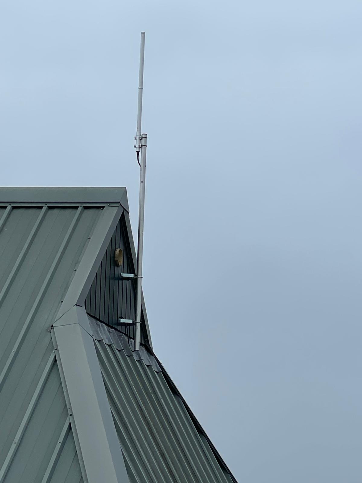 Antenna mast mounted on a green gable end