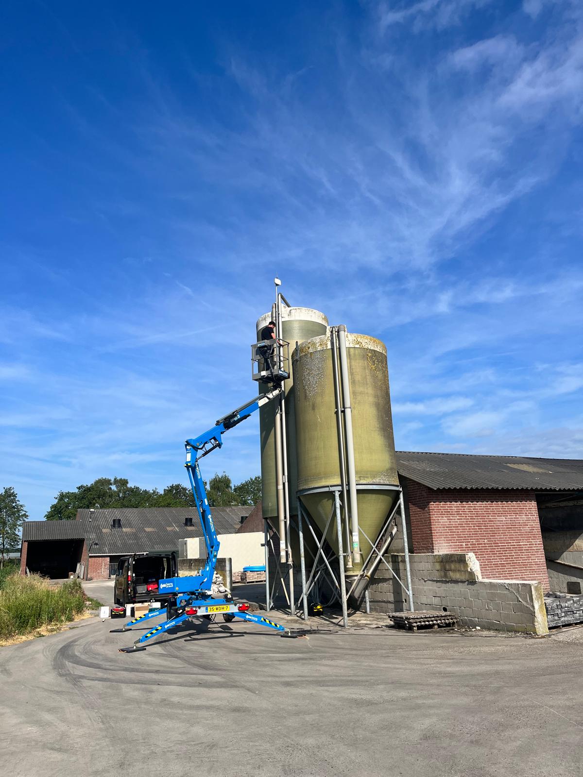Engineer on a cherry picker installing a gateway on a farm silo