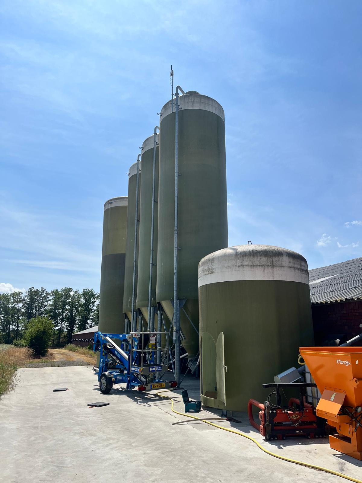 Farm silos with antenna and cherry picker on site