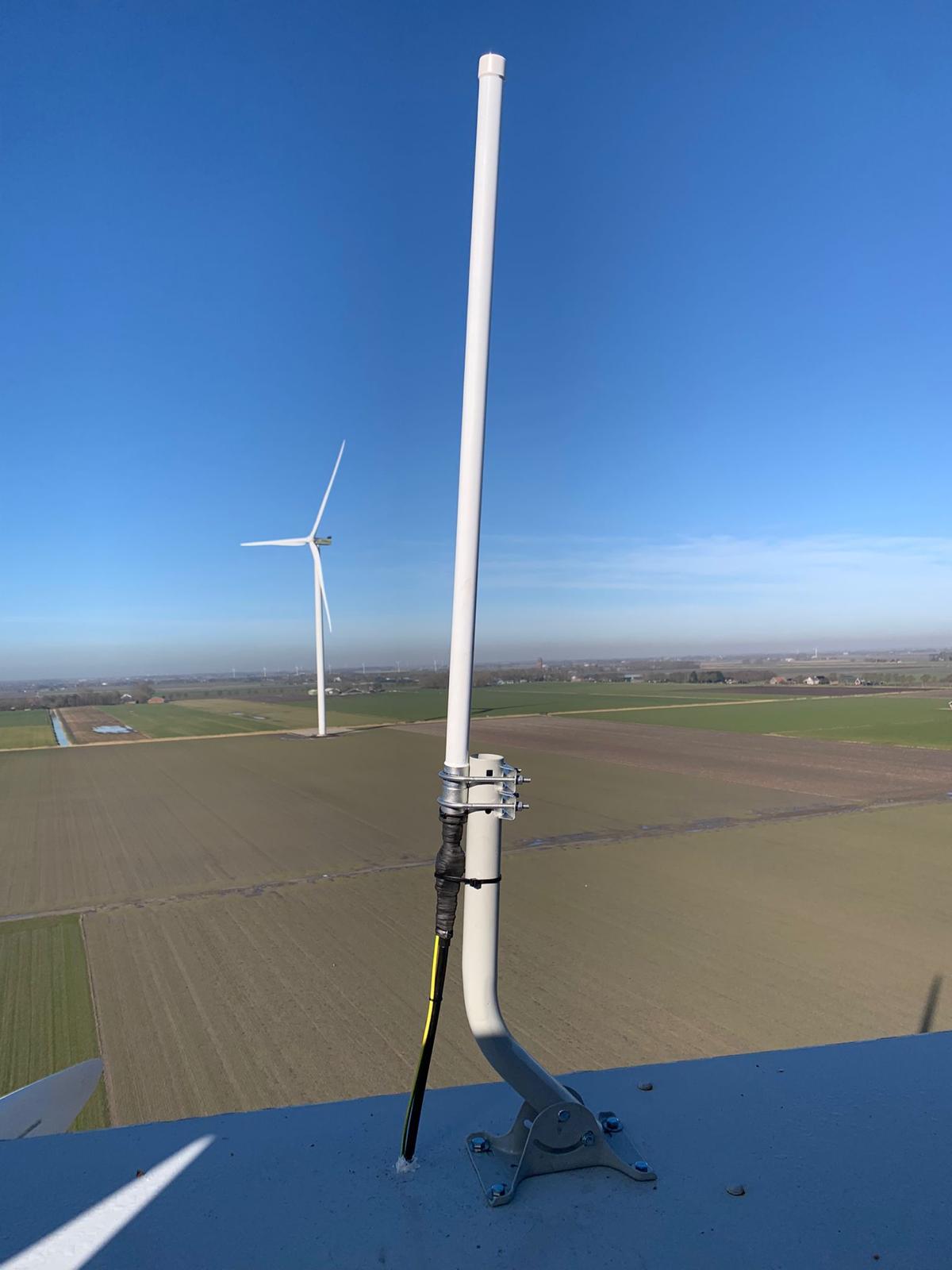 Antenna mounted on a wind turbine overlooking flat farmland