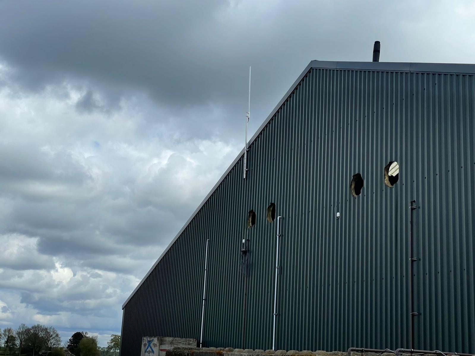 Antenna mast on a green metal warehouse